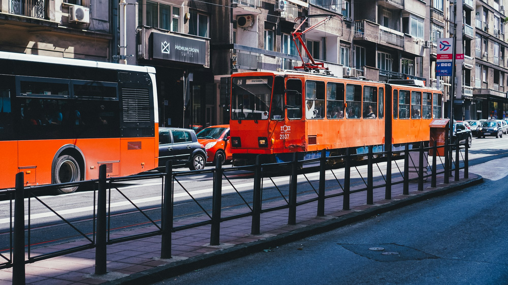 Gradski autobus i tramvaj u sunčanoj ulici