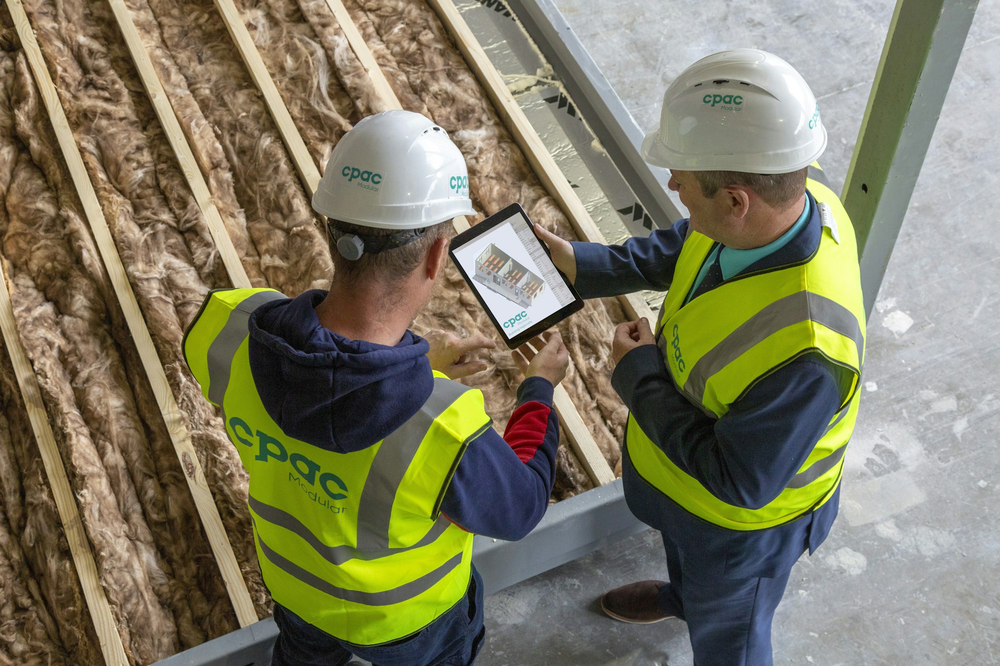 Dva radnika na gradilištu pregledaju planove na tabletu